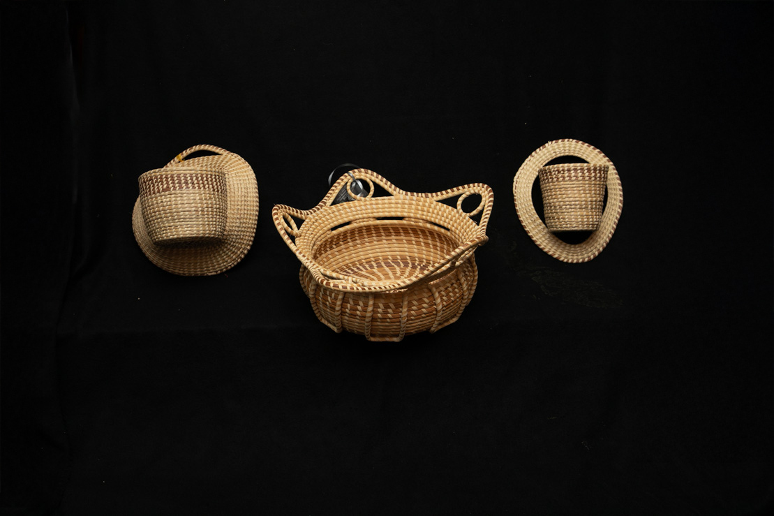Three small sweetgrass baskets with handles on black
