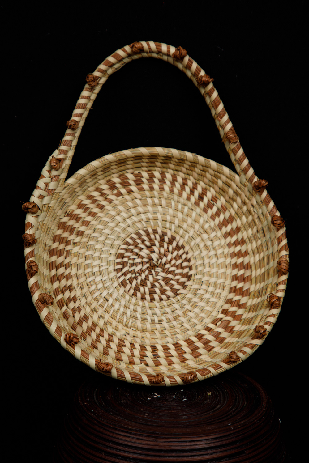 Round sweetgrass basket with a tall handle and palmetto knots